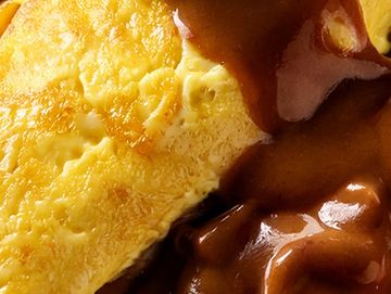 Close-up of a cheesy omelette with brown gravy.