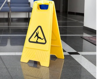 Yellow caution sign warns of slippery floor inside a building.