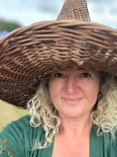 Woman wearing a large woven sun hat outdoors.