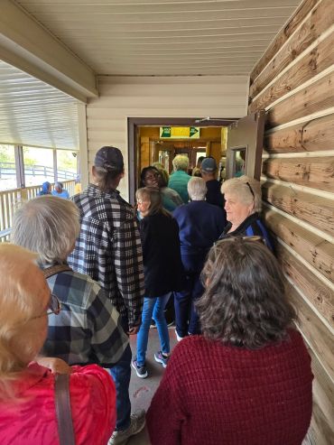 People standing in line outside a rustic building entrance.