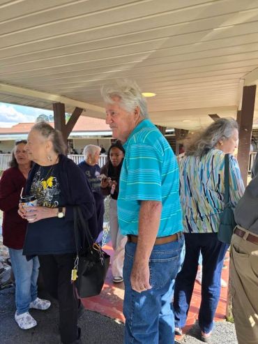 Group of older adults socializing outdoors under a covered area.