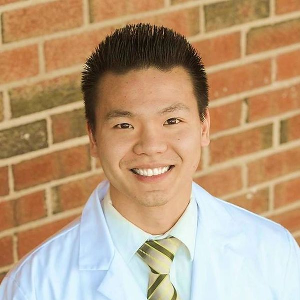 Smiling man in a white coat and striped tie.