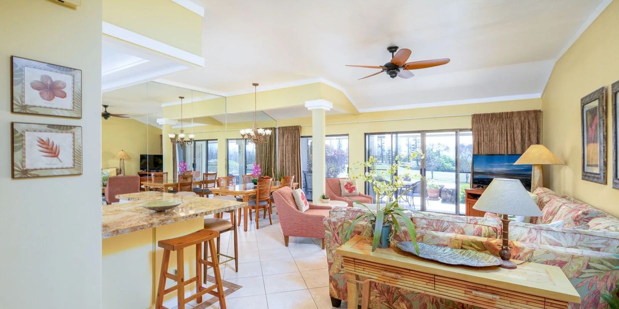 Bright, tropical-themed living room and dining area with floral upholstery and large windows.