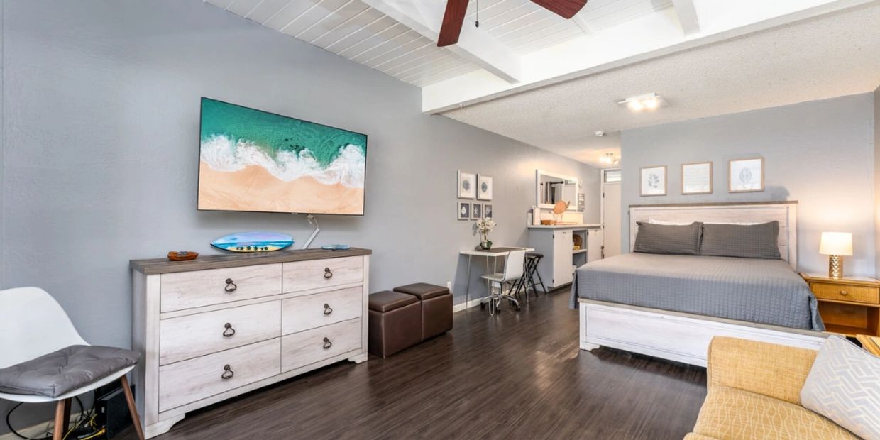 Modern studio apartment with beach-themed decor and wooden flooring.