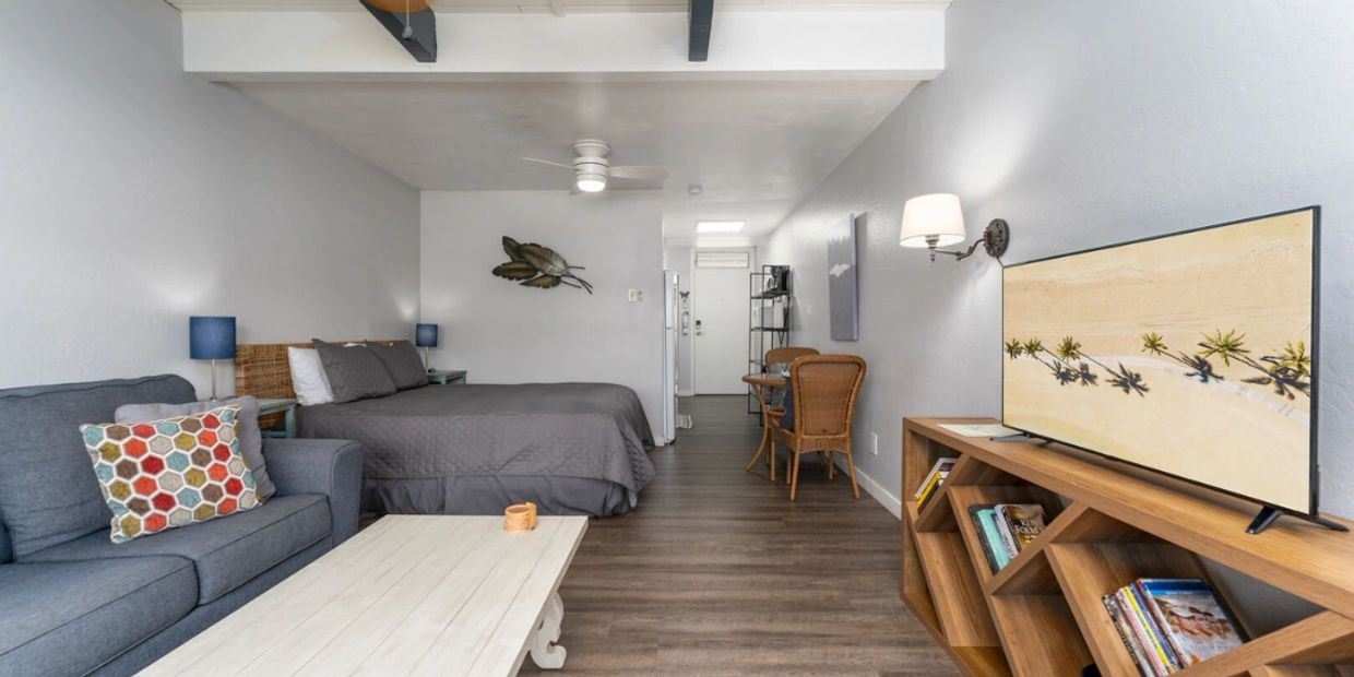 Modern studio apartment with gray decor and wooden furniture.