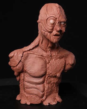 A creature maquette sculpted out of Chavant clay to show a melting man with exposed muscles