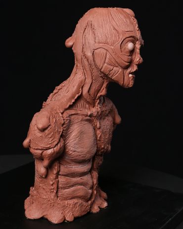A creature maquette sculpted out of Chavant clay to show a melting man with exposed muscles