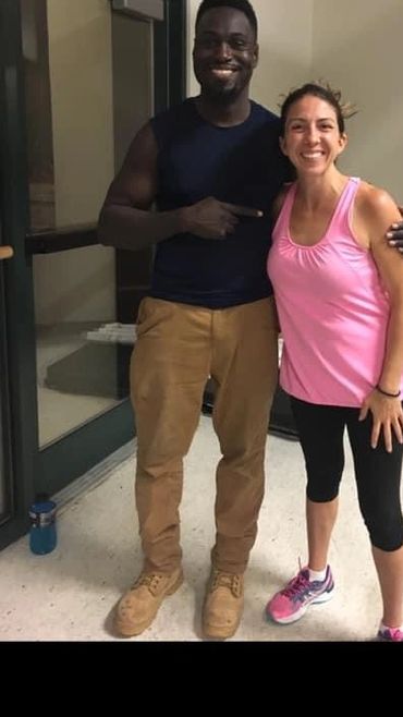 Two friends smiling, one in a pink tank top and the other pointing at her.
