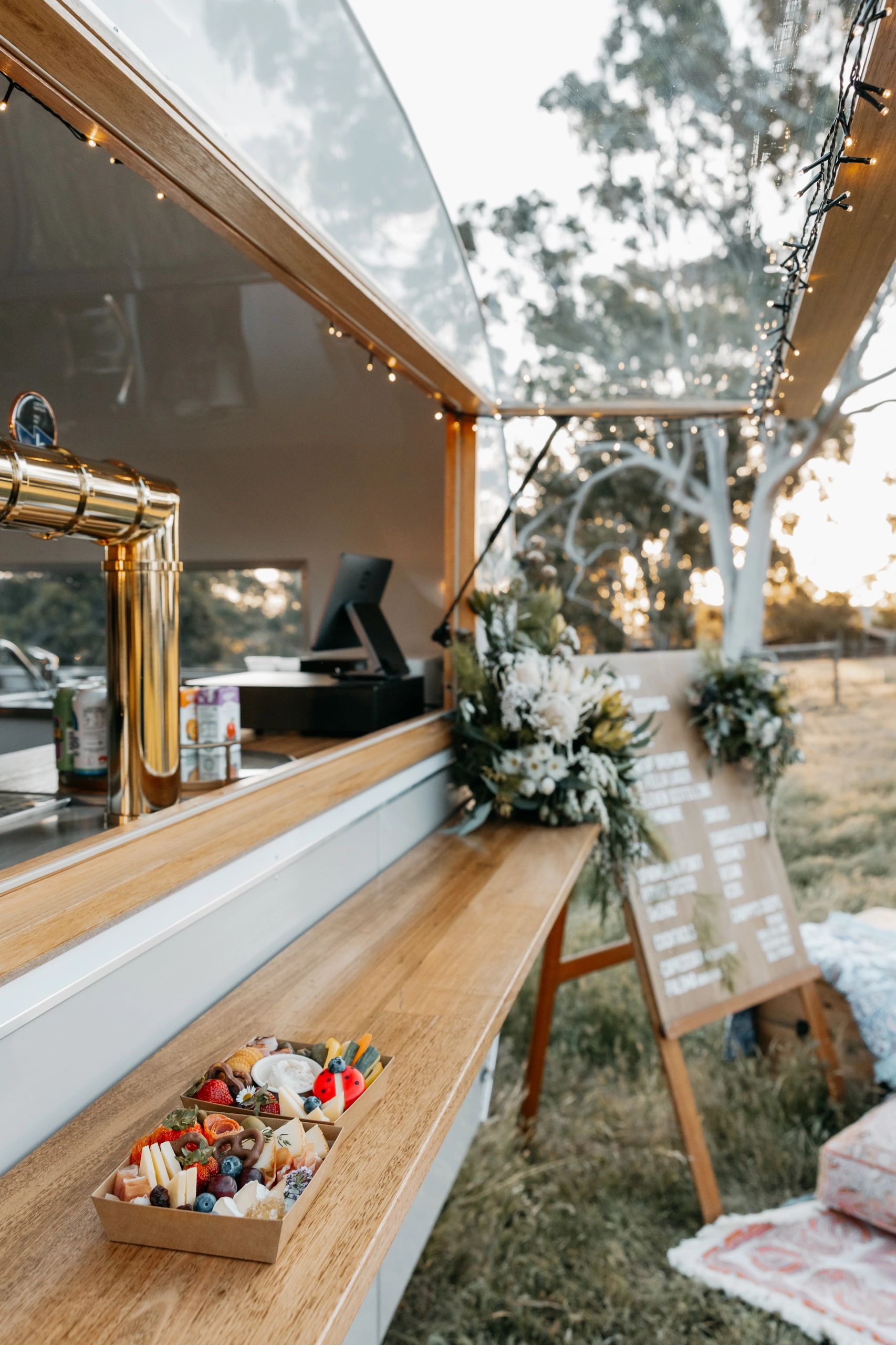 Outdoor bar with a gourmet snack box and floral decor at sunset.