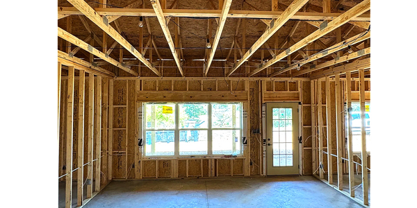 Barn House Co interior of a house under construction showing wooden framing and a concrete floor.