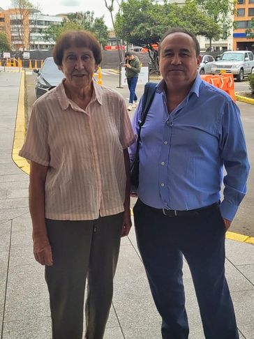 Two middle-aged people standing outdoors in a city setting.