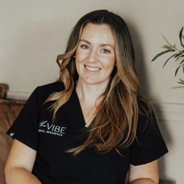 Smiling woman in black medical scrubs sitting indoors.