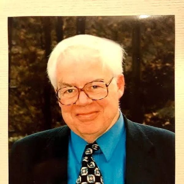 Smiling elderly man with white hair and glasses.