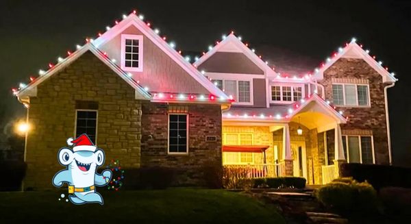 A house decorated with red and white Christmas lights at night.