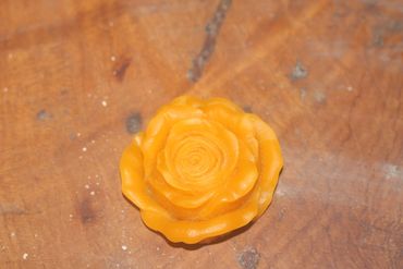 An orange rose-shaped object on a wooden surface.