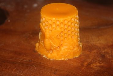 Ornate orange beeswax candle with honeycomb and bee design.