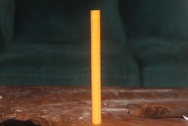 A tall honeycomb-patterned candle on a wooden surface.