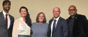 Group of five people posing and smiling.