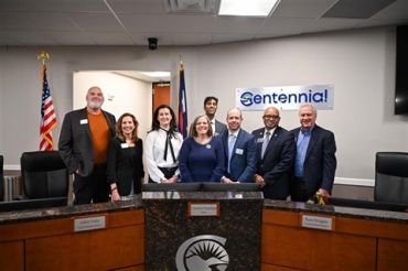 Group photo of eight people at Centennial meeting room.