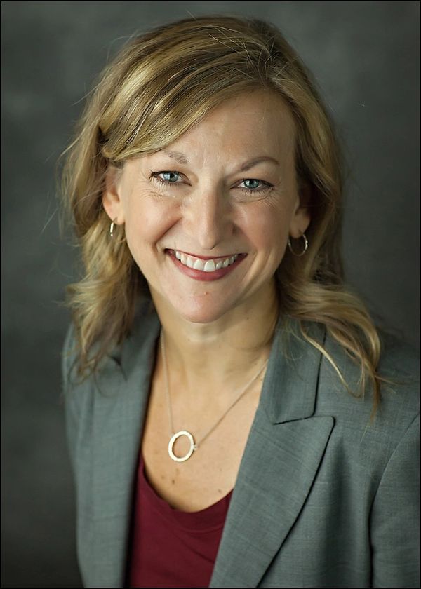 Smiling middle-aged woman in business attire.