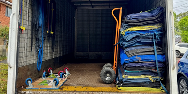 Open truck with stacked moving blankets and a hand truck inside.