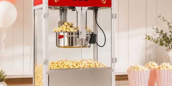 A popcorn machine dispensing freshly popped popcorn into a tray.