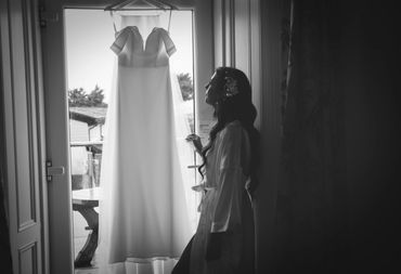 Black and white image of bride admiring her wedding dress