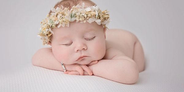 sleepy baby lying on tummy, resting on their arms with as floral halo headband