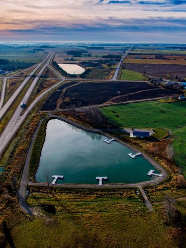Aerial view of rural landscape with a small lake and highway.
