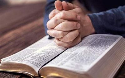 Hands clasped in prayer over an open Bible.