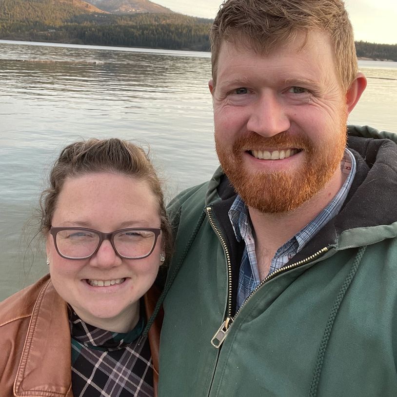 Couple smiling by a lake during sunset.