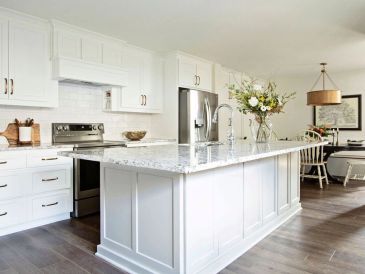 Bright modern white kitchen with large island and flowers.