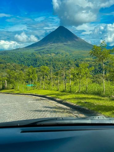 View of a lush green landscape and a mountain under a bright blue sky.