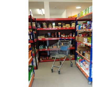 An empty supermarket trolley in front of stocked shelves in the  Community Store.