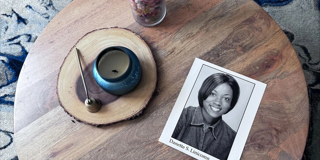 Wooden table with a candle, candle snuffer, and a black-and-white portrait photo.