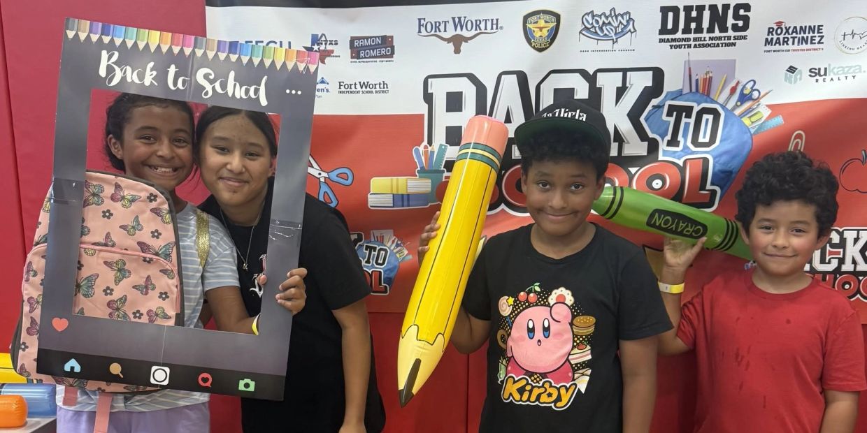 Kids posing with back to school props and smiling.