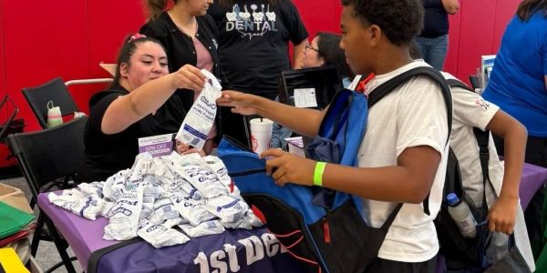 Child receiving dental supplies at a community event.