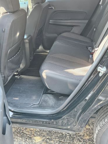 Clean rear seats and floor mats of a black car with door open.