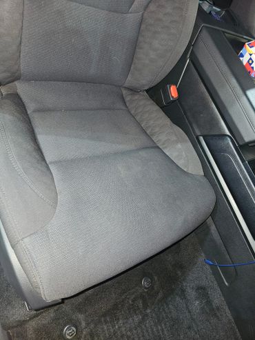 Close-up of a black car seat with surrounding interior details.