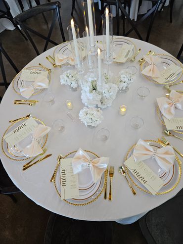 Elegant round table setting with candles and white flowers.