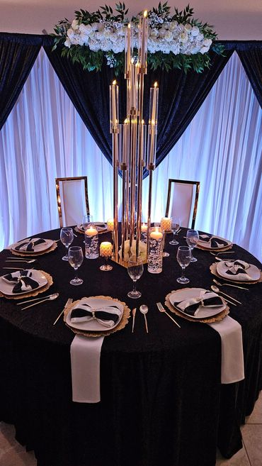 Elegant black and white formal dining setup with candles and floral centerpiece.