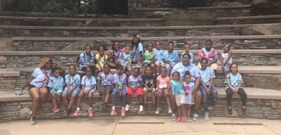 A group of children and adults sitting on stone steps outdoors.