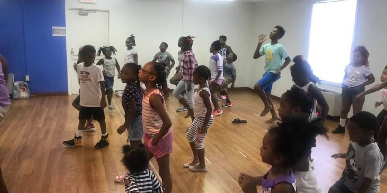 Children engaged in a dance class in a studio with wooden floors.