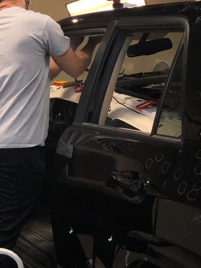 A man if fixing hail damage on a black car.