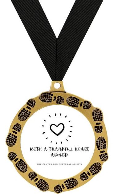 Gold circle meda with a black ribbon, with a hand drawn heart in the center and the words, 'With a T