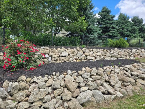 Tiered rock garden with red flowers and greenery.