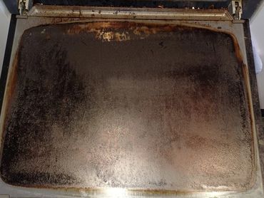 Dirty oven door with burnt residue and grime.