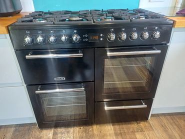 A modern black gas stove with multiple burners and dual ovens.