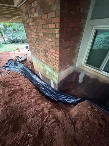 Foundation wall sealed and French drain trench at the basement window after water intrusion