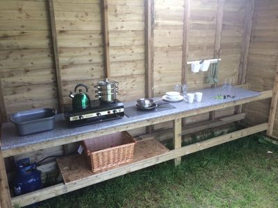 Covered kitchen area, with cooking stove , pots and pans and crockery